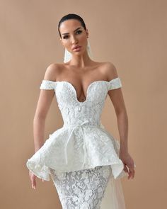 a woman in a white wedding dress with an off the shoulder neckline and ruffled skirt