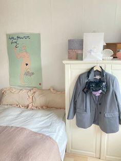 a bed room with a neatly made bed and a coat hanging on the wall next to it