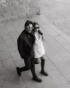 black and white photograph of two people walking down the street with sunglasses on their faces