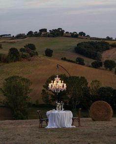 a chandelier hanging over a table in the middle of a field