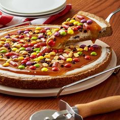 a cake covered in candy sits on a plate next to a fork and spoons