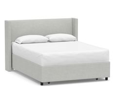 an upholstered bed frame with white pillows