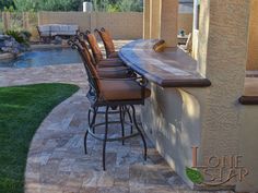 an outdoor bar with stools next to a pool