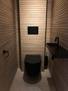 a small bathroom with two sinks and a toilet in the corner, along with wooden slats on the walls