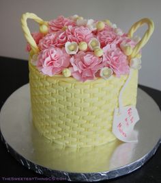 a cake decorated with pink flowers and candy canes in a basket on top of a table