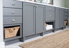 a bathroom with gray cabinets and baskets on the floor