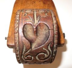 an old wooden box with a carved heart on the front and sides, sitting on a white surface