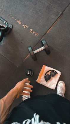 a person sitting on the ground with their feet up next to some dumbbells