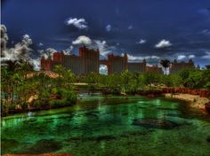 an image of a river that is green and blue in the day time with buildings on the other side