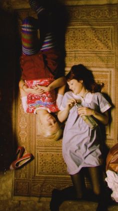 two people laying on the floor next to each other and one is holding a baby