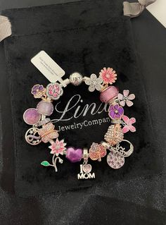 a bracelet with charms on it sitting in a velvet bag next to a tag that says linda jewelry company