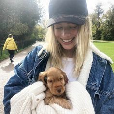 a woman holding a puppy in her arms while wearing a hat and blue jean jacket