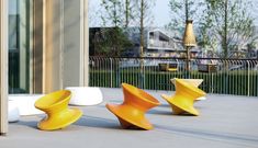 three yellow and white chairs sitting on top of a cement floor next to a building