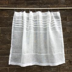 a white curtain hanging on a brick wall