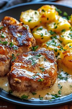 some meat and potatoes on a plate with gravy over it, ready to be eaten