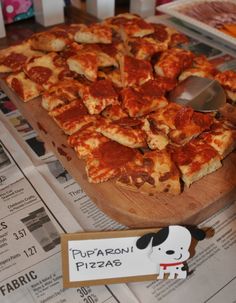 a pizza sitting on top of a wooden cutting board next to a sign that says papaoni pizzas