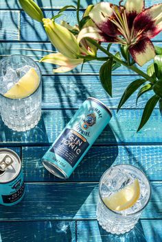 two cans of beer and some glasses on a blue wooden table