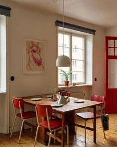 a dining room table with chairs and a red phone booth in the corner next to it