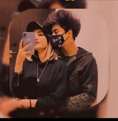 a man and woman taking a selfie in front of a mirror while wearing masks