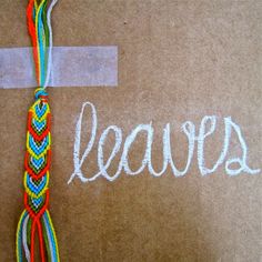 the word leavers written in white chalk on a brown background with colorful braiding