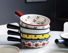 four colorful bowls stacked on top of each other with spoons in front of them