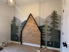 a room that has some trees painted on the wall and is being decorated with wood