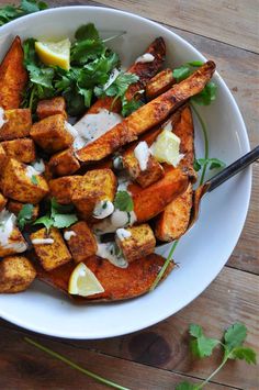 a white bowl filled with food on top of a wooden table next to a fork