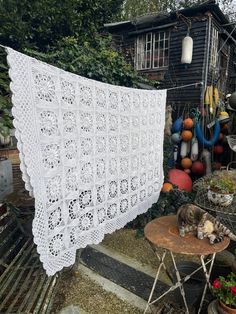 a white crocheted doily is hanging on a clothes line in front of a house