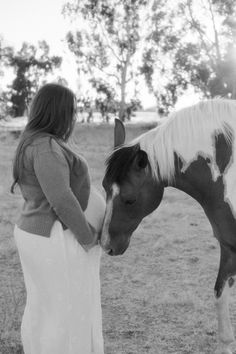 a woman standing next to a brown and white horse