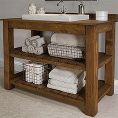 a bathroom sink sitting under a mirror next to a wooden shelf filled with white towels