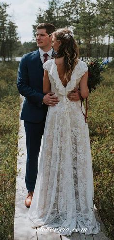 a man in a suit and tie walking down a path next to a woman in a wedding dress