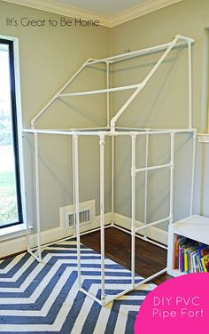 a white house made out of pipes in a room with a blue and white rug