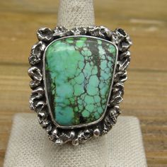 "Heavy Green turquoise statement ring. This is a new design. The turquoise stone is surrounded by silverwork. The artist is Jose Campos, and his hallmark (JC) and \"sterling\" are stamped on the underside of this ring. The turquoise stone measures 1 1/8\" by 7/8\". The whole face of the ring measures 1 1/2\" by 1 1/4\". The height of the ring measures 7 mm off the finger. The double split shank measures 5 mm. The ring is heavy, weighing 23.5g. The ring size is 8.5. We can size most rings for an Turquoise Statement Ring, Split Shank, Green Turquoise, Turquoise Stone, Statement Ring, Rings Statement, New Design, Turquoise Bracelet, Stone Color