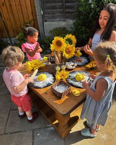 a group of children standing around a table with sunflowers on it