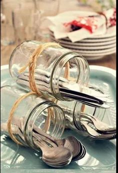 two glass jars with spoons and forks tied to each other on a blue plate