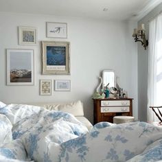 a bed with blue and white comforter in a bedroom next to pictures on the wall