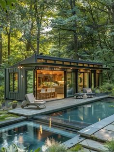 a small pool house in the middle of a forest with chairs and tables around it