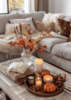 a tray with candles and pumpkins on top of a table in front of a couch