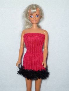 a doll with blonde hair wearing a red dress and black feathered skirt, standing in front of a white wall