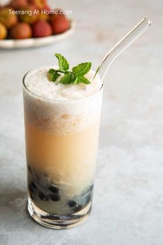 a drink with ice and mint garnish in a tall glass on a table