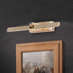 a painting hanging on the side of a wall next to a light fixture and framed artwork