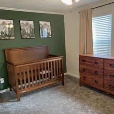 a baby crib and dresser in a room with green walls, carpeted floor