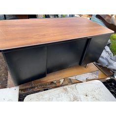 a large wooden table sitting on top of a metal grate next to a pile of junk