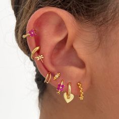 a woman wearing gold ear cuffs with pink flowers and hearts on the inside of them