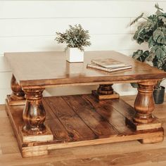 a wooden coffee table sitting on top of a hard wood floor next to a potted plant