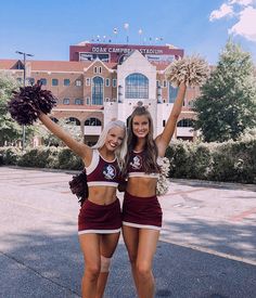 two cheerleaders posing in front of a stadium