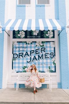 a woman sitting on a white bench in front of a blue and white striped building