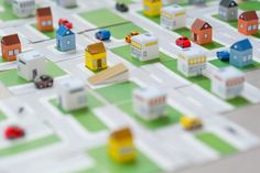 a toy city with cars, trucks and houses on the street is shown in close up