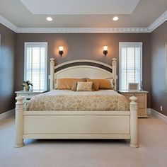 a large bed sitting inside of a bedroom next to two windows with white shutters