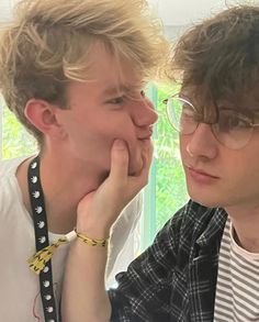 two young men sitting next to each other with their hands on their chins and looking at the camera